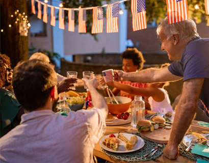 Family, friend, and neighbors gathering at a table for 4th of July cookout