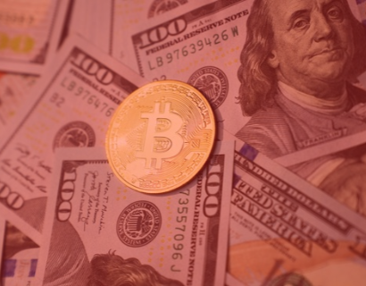 A red tinged photo of a bitcoin alongside 100-dollar bills.