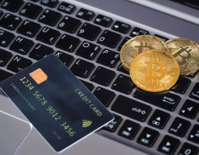 Image of a bitcoin and credit card on a laptop.